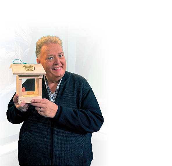 Person h lt ein kleines h lzernes Vogelhaus mit einem Dach und einem offenen Fach