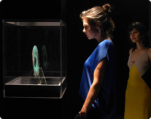 ARD Degeto DAS DUNKLE VERM CHTNIS, am Samstag (14.03.26) um 20:15 Uhr und um 01:15 Uhr im ERSTEN, online first ab Donnerstag (12.03.26) in der ARD MEDIATHEK Ein t dlicher Fluch? Die Hamburger Fotografin Kim Wenrich (Felicitas Woll, li.) und Museumsleiterin Rebecca Rosen (Neda Rahmanian, re.) vor der Himmelsscheibe von Nebra. © ARD Degeto Film/ARD Degeto Film/MadeFor Film GmbH/Hans-Joachim Pfeiffer, honorarfrei - Verwendung gem  der AGB im engen inhaltlichen, redaktionellen Zusammenhang mit genannter Degeto-Sendung und bei Nennung “Bild: ARD Degeto Film/ARD Degeto Film/MadeFor Film GmbH/Hans-Joachim Pfeiffer" (S2+). ARD Degeto/Programmplanung und Presse, Tel: 069/1509-335, degeto-presse@degeto.de