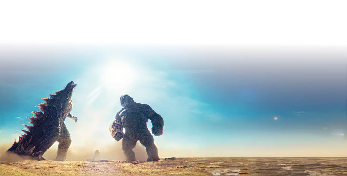 Das Bild zeigt eine dramatische Filmszene in einer weiten, trockenen Ebene. Links steht ein massives, dunkelgraues Reptilienmonster mit schuppiger Haut und gro en, hell leuchtenden R ckenstacheln; es ist leicht nach hinten gelehnt und hat das Maul ge ffnet, als w rde es br llen. Rechts steht ein riesiger Gorilla mit dichtem, dunklem Fell, der ebenfalls br llend nach oben blickt. An seinem rechten Unterarm tr gt er eine gro e, metallische, handschuhartige Vorrichtung. Zwischen den beiden Figuren liegt Staub in der Luft; im Hintergrund dominiert ein helles, grelles Sonnenlicht vor blauem Himmel, das die Szene von hinten stark berstrahlt.