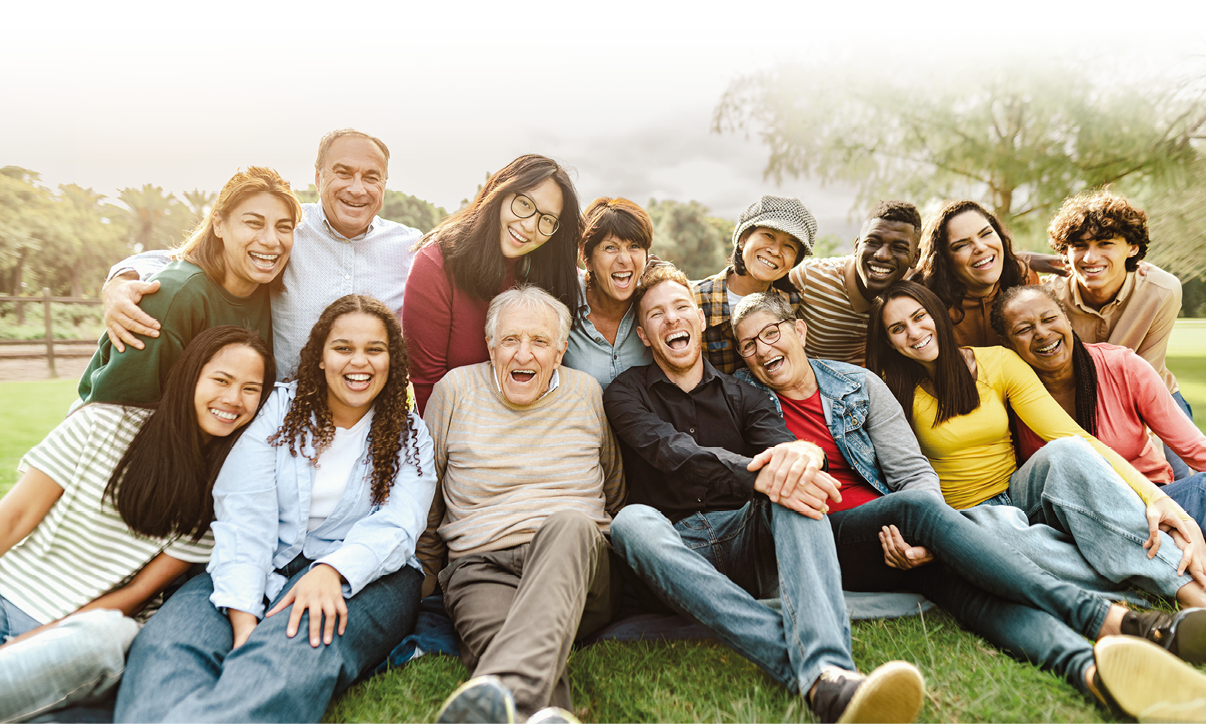 Happy multigenerational people having fun sitting on grass in a public park