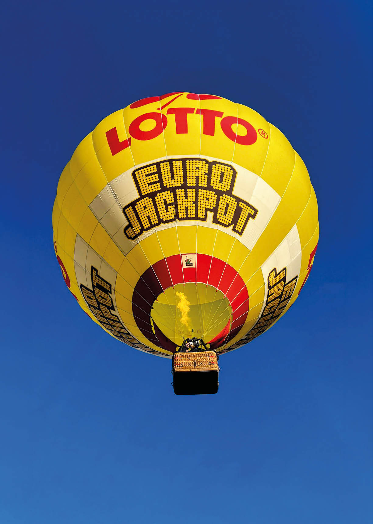 Ein gelber Hei luftballon mit der Aufschrift Lotto Euro Jackpot fliegt vor einem klaren blauen Himmel. Beschreibung von KI generiert